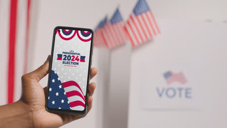 Nahaufnahme-Einer-Hand,-Die-Ein-Mobiltelefon-Mit-Bildschirm-Hält-Und-Die-Menschen-Dazu-Ermutigt,-Bei-Den-US-Präsidentschaftswahlen-2024-Zu-Wählen